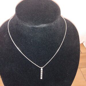 Silver tone chain necklace with black and clear rhinestone dangle pendant.